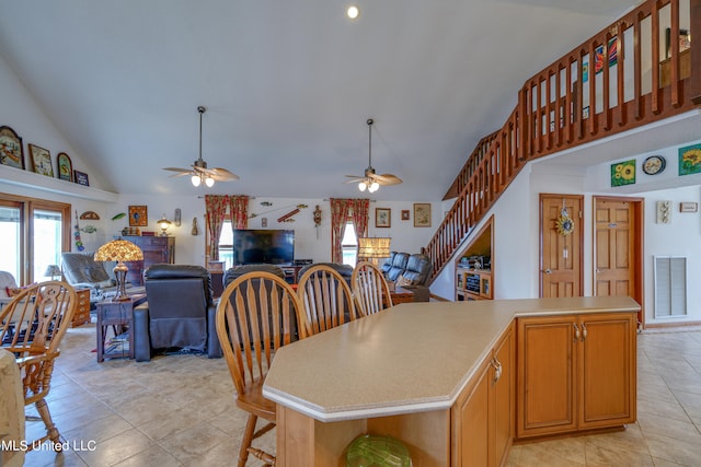 kitchen with a center island, high vaulted ceiling, light tile patterned floors, and ceiling fan