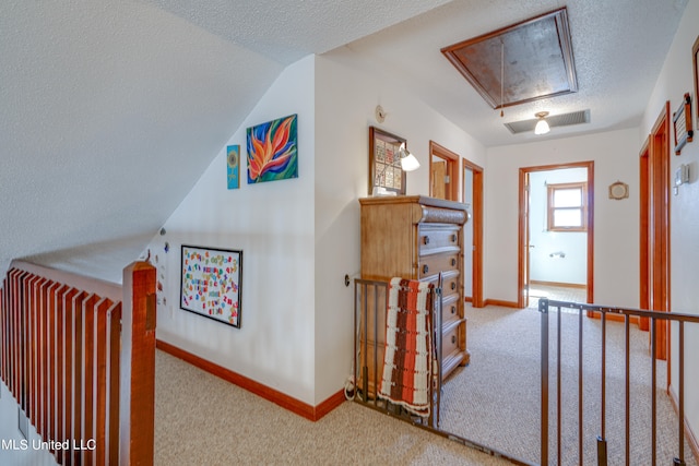 hallway featuring lofted ceiling, a textured ceiling, and light colored carpet