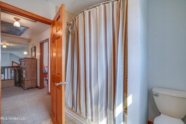 bathroom with toilet, a textured ceiling, and walk in shower