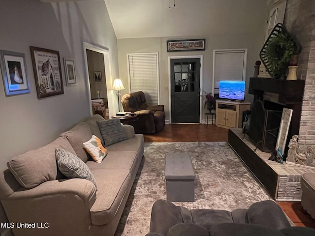 living room featuring a brick fireplace, vaulted ceiling, and wood finished floors