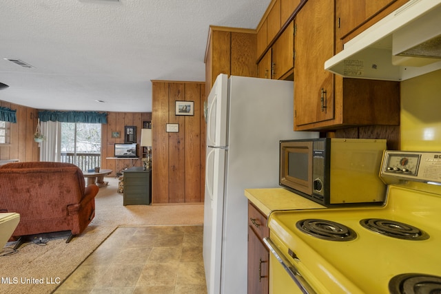 kitchen with light carpet, range, a textured ceiling, and wood walls