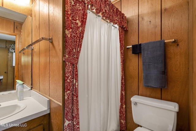 bathroom with vanity, wooden walls, and toilet