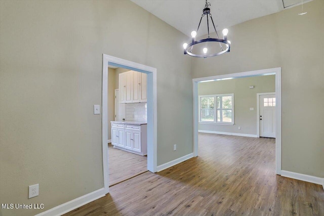 1204 Jackson St, Vicksburg, MS 39183 - unfurnished dining area featuring wood finished floors, high vaulted ceiling, attic access, a notable chandelier, and baseboards