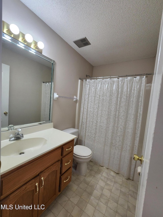 bathroom with vanity, toilet, a textured ceiling, and curtained shower