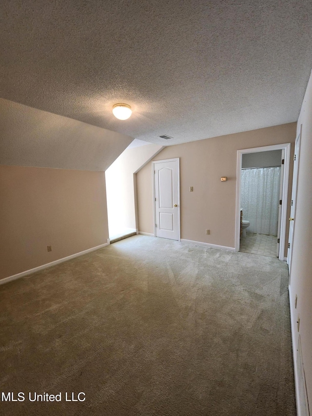 bonus room featuring lofted ceiling, a textured ceiling, and carpet flooring