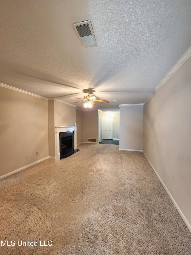 unfurnished living room featuring a tiled fireplace, ornamental molding, carpet, a textured ceiling, and ceiling fan