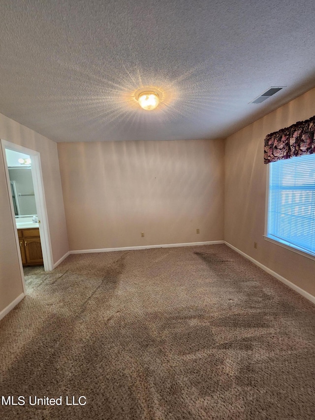 empty room featuring a textured ceiling and carpet