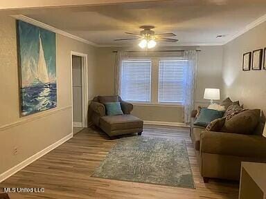 living area with wood-type flooring, ceiling fan, and crown molding