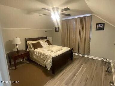 bedroom with ceiling fan, lofted ceiling, and hardwood / wood-style flooring