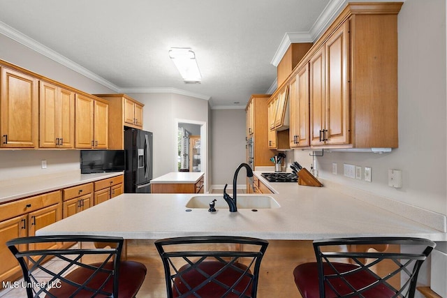 kitchen with ornamental molding, a breakfast bar area, kitchen peninsula, and black fridge with ice dispenser