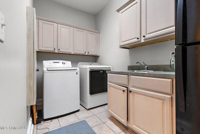 clothes washing area featuring sink, washer and clothes dryer, light tile patterned floors, and cabinets