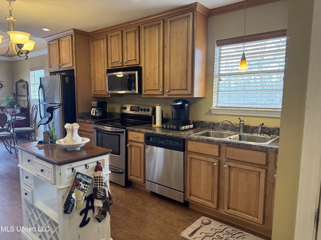 kitchen with dark wood-type flooring, sink, crown molding, appliances with stainless steel finishes, and pendant lighting