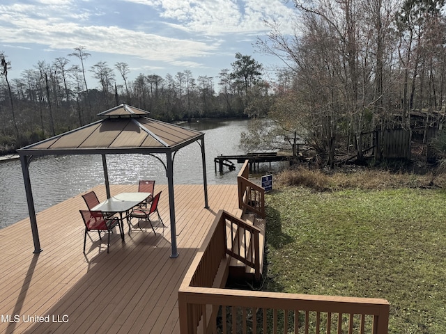 view of dock with a gazebo, a lawn, and a water view