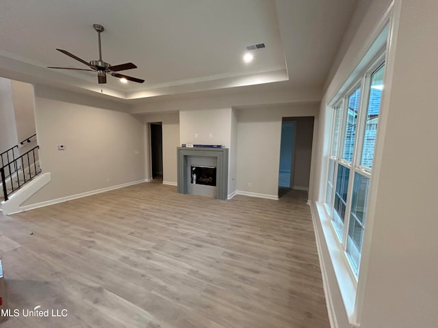 unfurnished living room with ceiling fan, a raised ceiling, and light hardwood / wood-style flooring