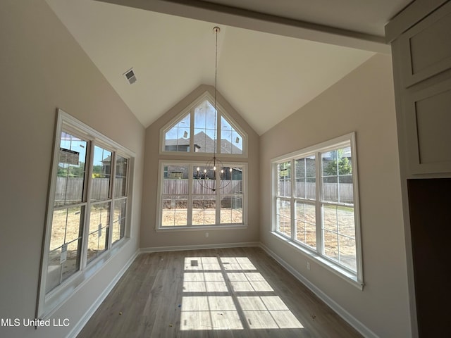 unfurnished sunroom featuring lofted ceiling, a chandelier, and a healthy amount of sunlight