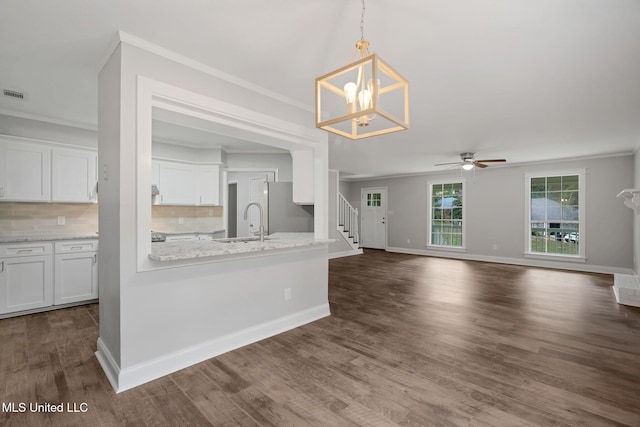 kitchen with white cabinets, light stone counters, crown molding, and backsplash