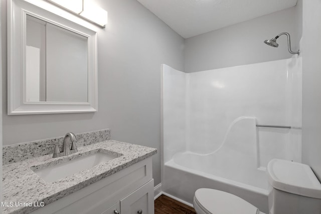 full bathroom with hardwood / wood-style floors, vanity,  shower combination, and toilet