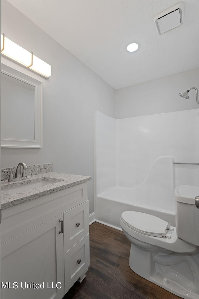 full bathroom featuring hardwood / wood-style floors, vanity, tub / shower combination, and toilet