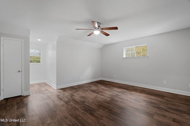 empty room with dark hardwood / wood-style flooring, a wealth of natural light, lofted ceiling, and ceiling fan