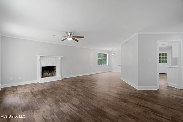 unfurnished living room with a fireplace, dark hardwood / wood-style floors, crown molding, and ceiling fan