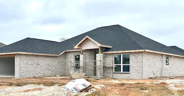 view of front of home with brick siding, a garage, and roof with shingles