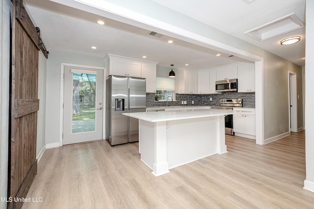 209 Audrey Cir, Ocean Springs, MS 39564 - kitchen with appliances with stainless steel finishes, a sink, light wood-type flooring, a barn door, and a kitchen island