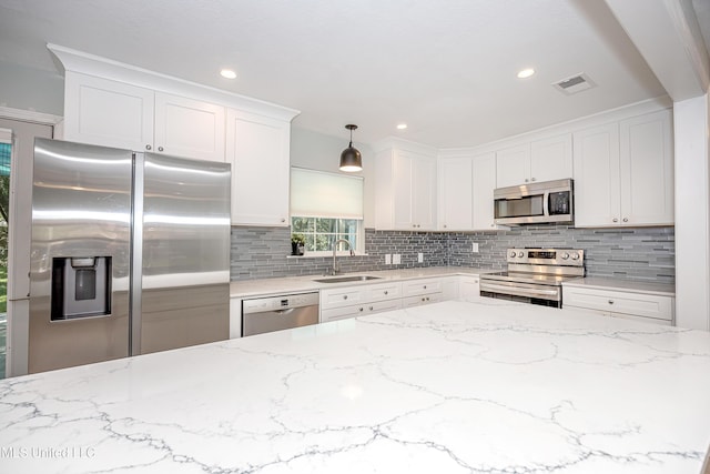 209 Audrey Cir, Ocean Springs, MS 39564 - kitchen with stainless steel appliances, a sink, backsplash, white cabinets, and light stone counters