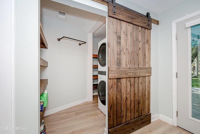 209 Audrey Cir, Ocean Springs, MS 39564 - laundry area with stacked washer / dryer, a barn door, wood finished floors, and baseboards