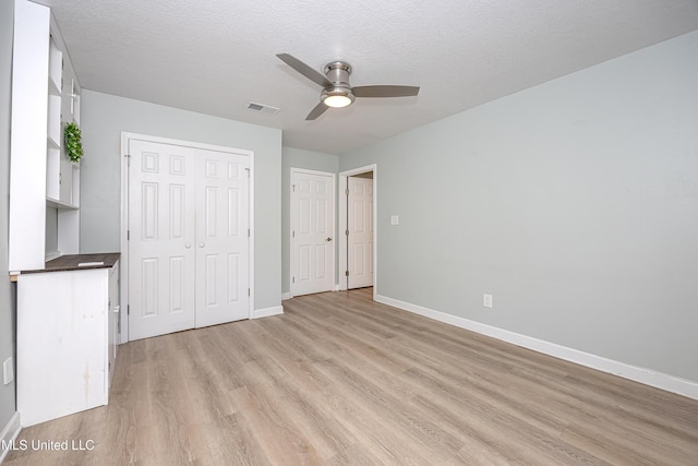 209 Audrey Cir, Ocean Springs, MS 39564 - unfurnished bedroom with light wood-type flooring, baseboards, a closet, a ceiling fan, and a textured ceiling