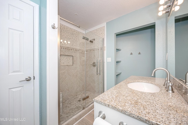 209 Audrey Cir, Ocean Springs, MS 39564 - bathroom featuring a shower stall, vanity, wood finished floors, and a textured ceiling