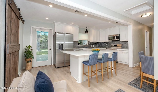 209 Audrey Cir, Ocean Springs, MS 39564 - kitchen with stainless steel appliances, a breakfast bar area, light wood-style floors, white cabinetry, and recessed lighting