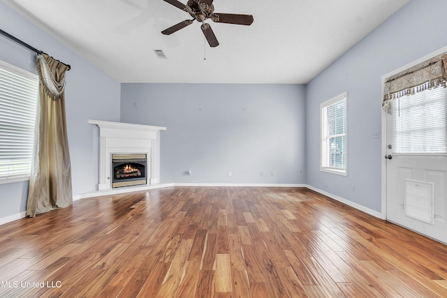 700 Martin Luther King Jr Dr, Holly Springs, MS 38635 - unfurnished living room featuring ceiling fan, wood finished floors, a warm lit fireplace, and baseboards