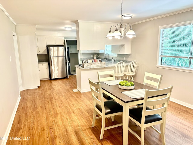 dining area featuring light hardwood / wood-style floors, crown molding, a chandelier, and sink