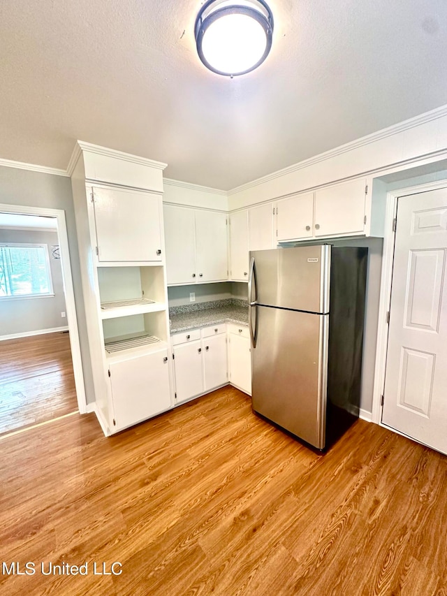 kitchen with a textured ceiling, white cabinetry, light hardwood / wood-style floors, crown molding, and stainless steel refrigerator