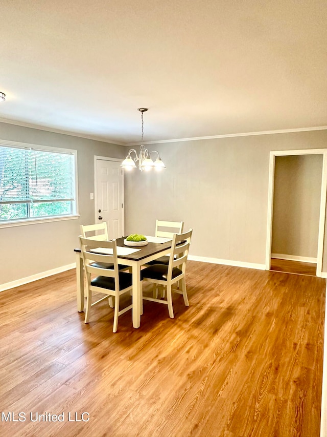 dining space featuring an inviting chandelier, ornamental molding, and wood-type flooring