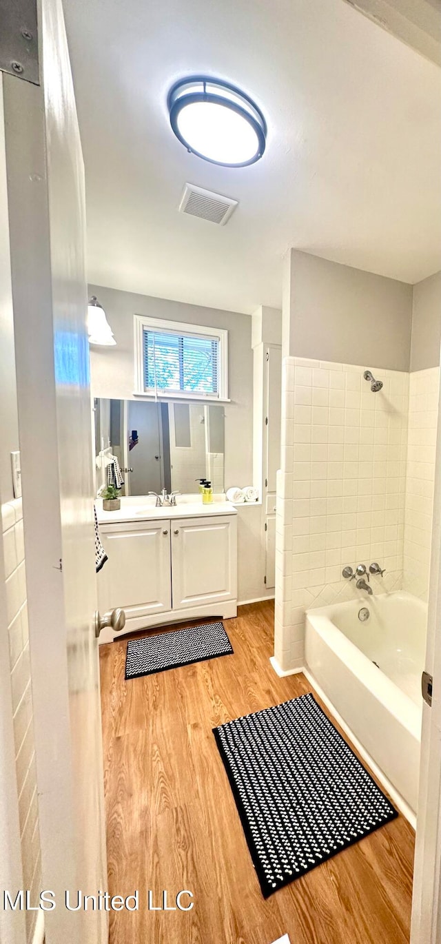 bathroom featuring vanity, a tub to relax in, and wood-type flooring