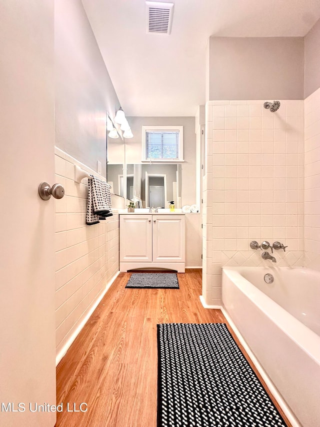 bathroom featuring vanity, hardwood / wood-style flooring, and tile walls