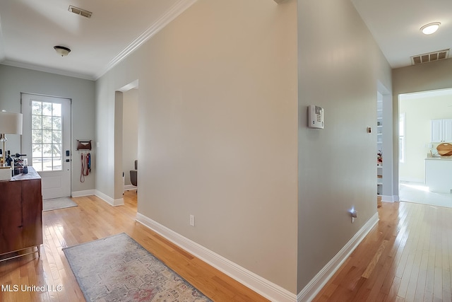 corridor with light wood-type flooring and ornamental molding