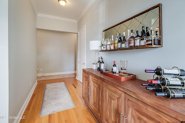 bar featuring light wood-type flooring, ornamental molding, and wood counters