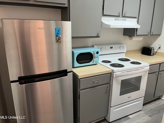 kitchen with light hardwood / wood-style flooring, gray cabinetry, stainless steel appliances, and range hood