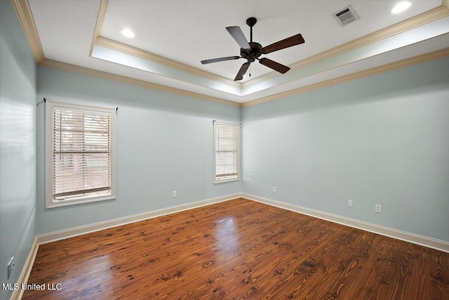 empty room featuring ornamental molding, ceiling fan, a tray ceiling, and dark hardwood / wood-style flooring