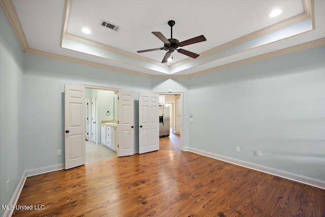 unfurnished bedroom featuring ceiling fan, light wood-type flooring, and a raised ceiling