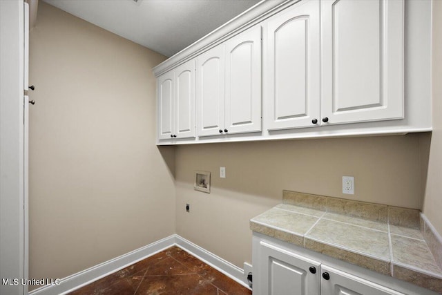 clothes washing area with dark tile patterned flooring, electric dryer hookup, washer hookup, and cabinets