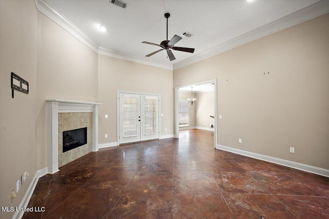 unfurnished living room with a towering ceiling, ceiling fan with notable chandelier, french doors, a tile fireplace, and ornamental molding