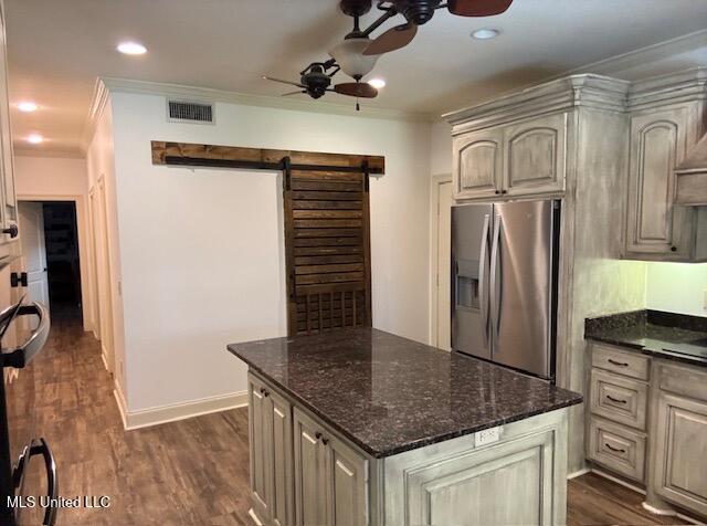 kitchen featuring a barn door, a ceiling fan, ornamental molding, dark wood-style floors, and stainless steel fridge