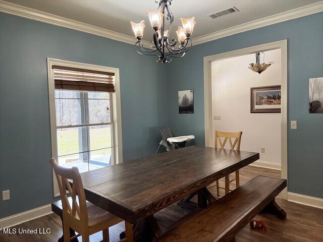 dining room with baseboards, visible vents, dark wood finished floors, an inviting chandelier, and crown molding