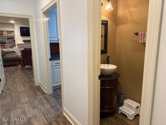 hallway featuring dark wood-style floors, a sink, and baseboards