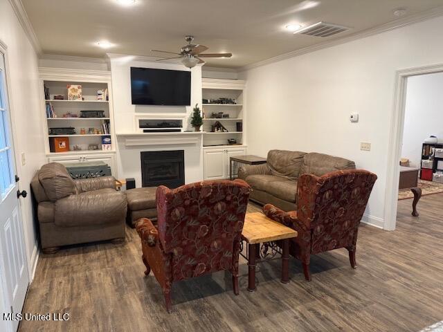 living room featuring visible vents, a ceiling fan, ornamental molding, wood finished floors, and a fireplace