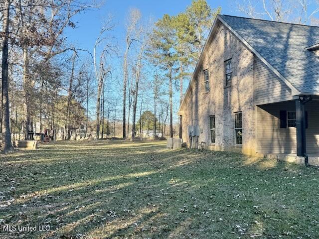 view of property exterior featuring roof with shingles and a lawn