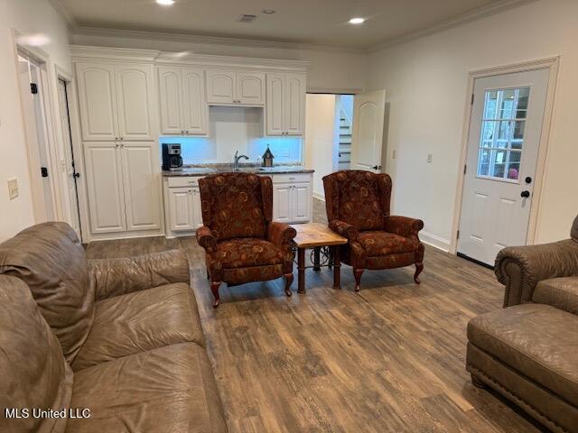 living area with baseboards, ornamental molding, dark wood-type flooring, and recessed lighting